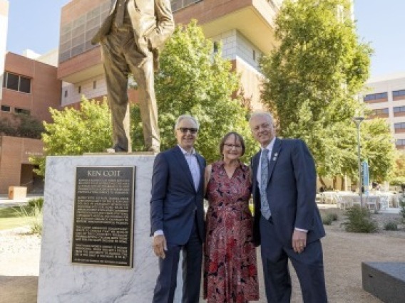A photograph of Ken and Donna Coit with Rick G. Schnellmann standing in front of the gold Ken Coit statue 