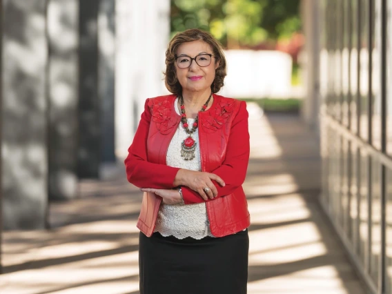 A woman smiling with her arms crossed, wearing a red jacket