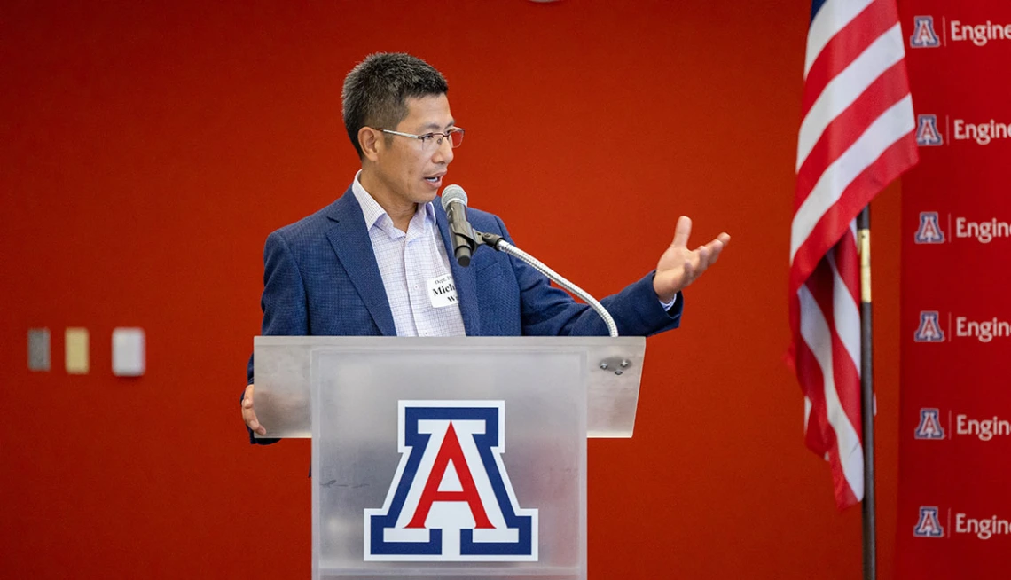 Michael Wu standing and speaking into a microphone, while standing in front of a podium with a "Block A" on it.