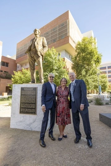 A photograph of Ken and Donna Coit with Rick G. Schnellmann standing in front of the gold Ken Coit statue
