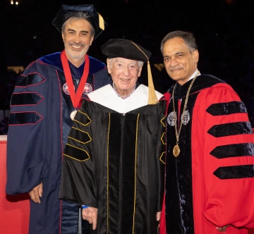 Three men standing and smiling in academic regalia